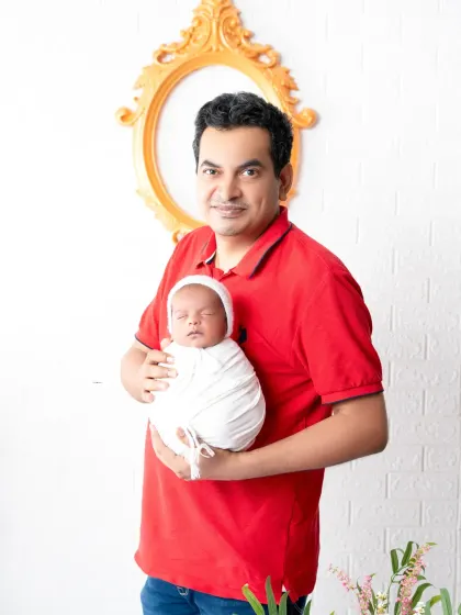 A proud father holds his swaddled newborn. These simple, heartfelt portraits focus on the powerful connection between a parent and their new baby.