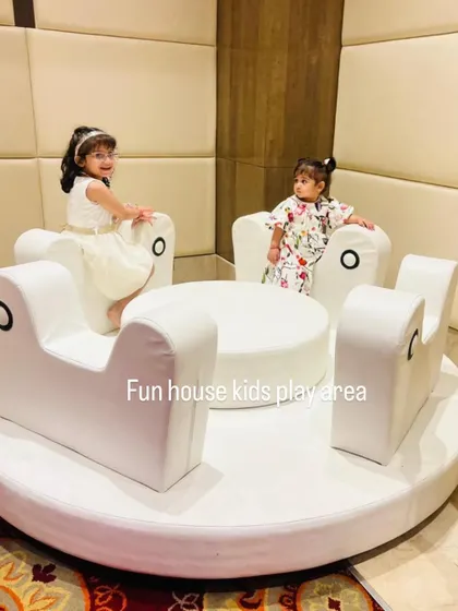 Two young girls seated on the plush, comfortable seats of the white merry-go-round.