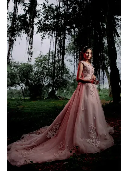 The long, flowing train of the pink wedding gown looks absolutely magical in a lush, green forest setting.
