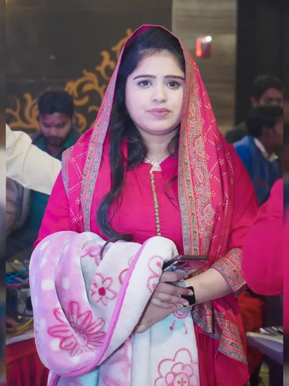A portrait of a woman in traditional pink attire, captured at a family event.