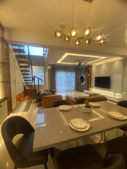 This view captures the entire open-plan ground floor, from the dining table to the living room and staircase. The cohesive design and lighting create a harmonious and expansive feel.