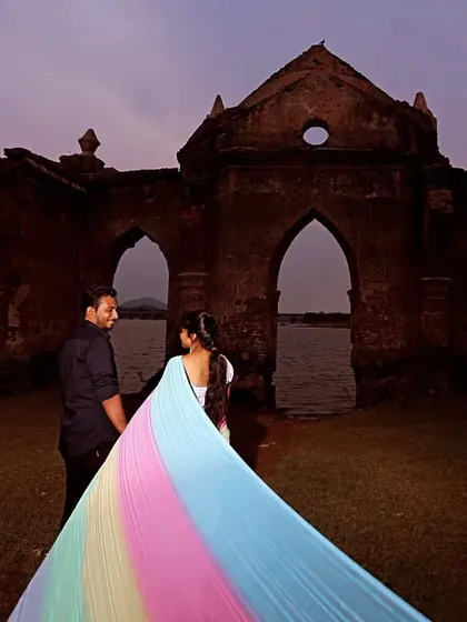 A unique pre-wedding shoot at the Shettihalli Rosary Church ruins. The client wears a saree with a long, flowing rainbow trail.
