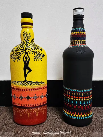 The yoga-themed bottle and the black dot-art bottle together, showcasing two very different styles of decorative bottle painting.