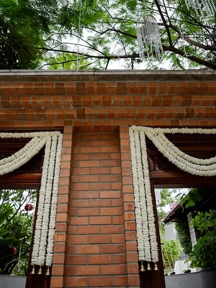 This wedding entrance features a stunning blend of fragrant tuberoses and earthy terracotta pots, with a personalized welcome board adding a warm touch.