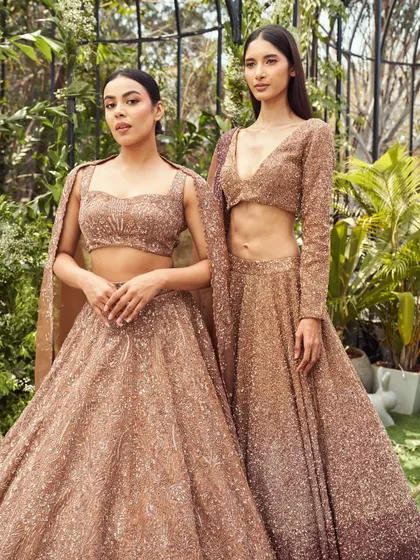 Two shimmering rose gold lehengas from the Lenora collection. With intricate handwork and flowing fabrics, this is minimalism made majestic, perfect for the modern bride or bridesmaid.
