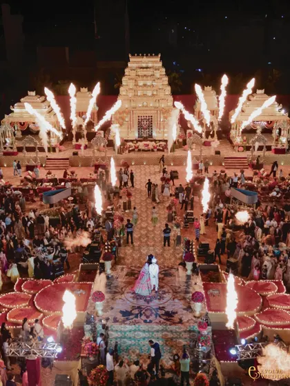 The climax of the ceremony, with pyrotechnics illuminating the temple-inspired mandap and the grand aisle. This bird's-eye view captures the energy and scale of an event where every detail was curated for a magical, immersive experience.