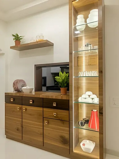 A beautiful crockery unit made from rich-grained wood. The design includes a tall, glass-fronted display cabinet with internal lighting, a serving counter, and ample drawer and cabinet space below.