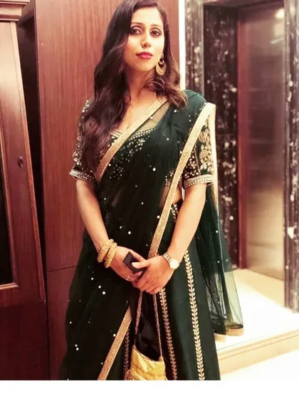A client looking poised in a dark green saree with a gold embroidered border and blouse. This is a timeless choice for attending a wedding or a formal dinner.