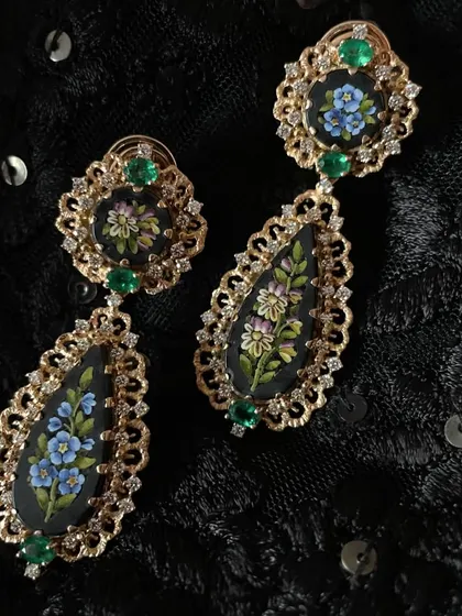 A studio shot of the micromosaic earrings worn by Shilpa Shetty. The floral design is set against a black background, framed with gold and emeralds, giving them a vintage, moody feel.