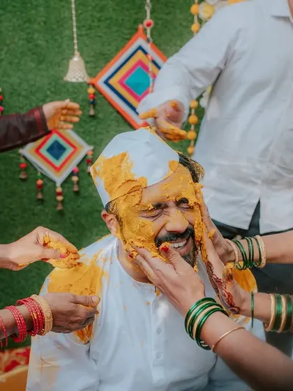The groom gets playfully covered in turmeric by his family during a fun-filled Haldi ceremony.