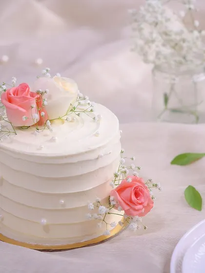 We believe that simple gestures are the most profound. This happy anniversary cake features a clean, white-frosted design, elegantly adorned with fresh pink and white roses, baby's breath, and delicate pearls for a look of pure and simple romance.