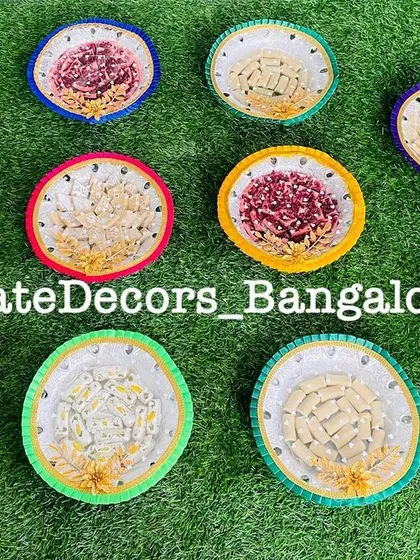 A collection of my decorated seer plates ready for an event. Each plate has a unique, colorful border and is filled with sweets.