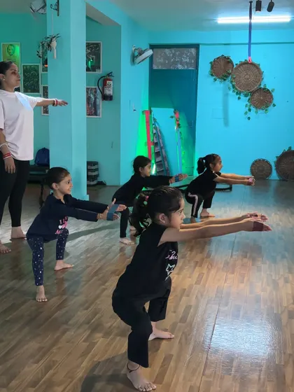 A group of young dancers practicing their squats in unison. This exercise builds leg strength and body control.