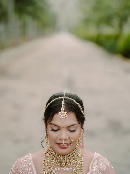 A serene close-up of the bride with her eyes closed, showcasing her intricate matha patti and flawless makeup.
