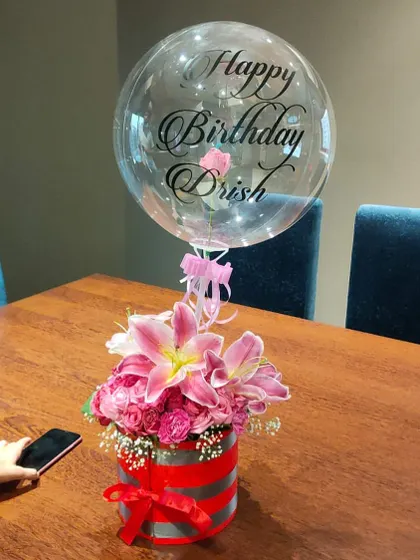 This was one of our early luxury hampers, and it's still a favorite. A personalized balloon floats above a striking red and silver box filled with exotic lilies and pink roses.