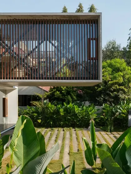 An exterior view of the Long House, where the cantilevered upper floor hovers above the landscape. Timber screens provide privacy while maintaining a visual connection to the garden.