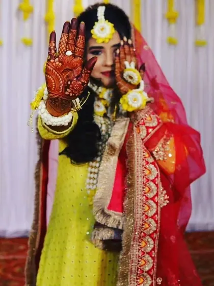 A candid moment with a beautiful bride on her haldi day. Her hands, adorned with a deep henna stain, perfectly complement the vibrant yellow of the ceremony.