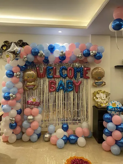 A full view of the 'Welcome Baby' balloon backdrop. The setup includes columns and an arch, with a silver tinsel curtain and foil balloons for a boy.