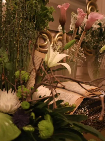 A soft-focus shot of a floral arrangement, showing the depth and layers we create by combining different textures, from delicate white lilies to rustic bare branches.
