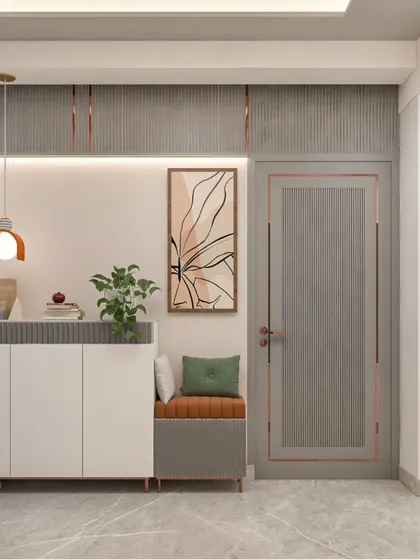The entryway of our Bhagalpur residence project, featuring a built-in shoe cabinet with a comfortable seating nook. The design uses a palette of grey and earthy orange, with fluted panels and modern lighting to create a welcoming first impression.