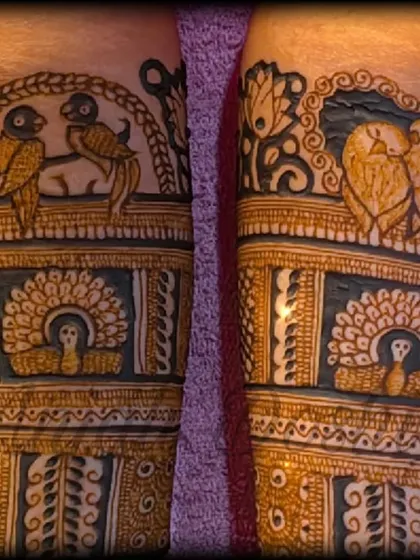 A close up of the fresh henna paste, showing the details of lovebirds and a bride figure before the design is complete.