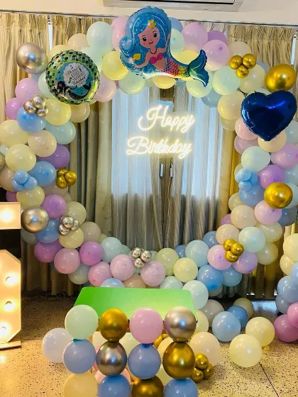 An enchanting mermaid-themed birthday party. This setup features a full balloon ring in pastel colors with a mermaid foil balloon, a "Happy Birthday" neon sign, and a light-up number "6".