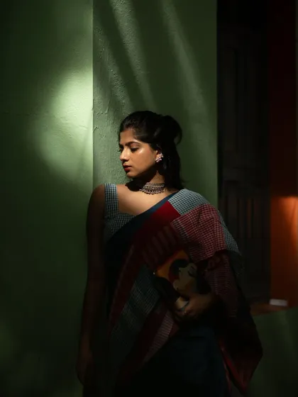A dramatic shot playing with light and shadow. The contemporary patchwork saree, paired with a modern blouse and clutch, creates a mysterious and artistic portrait.