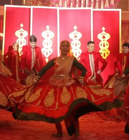 The energy of the dancers is a key part of the experience. Here, performers in vibrant red costumes perform a traditional dance with great energy, setting a festive mood for the varmala ceremony.