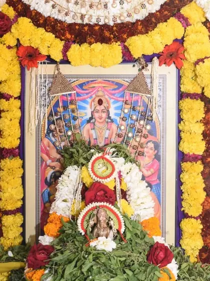 The beautifully decorated shrine for a Satyanarayana Puja, adorned with garlands of fresh flowers.