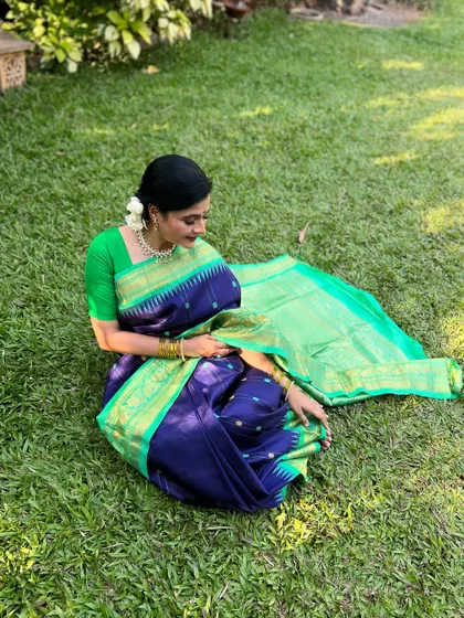A lovely shot of Bhargavi sitting on the grass, showcasing the beautiful drape of her saree.