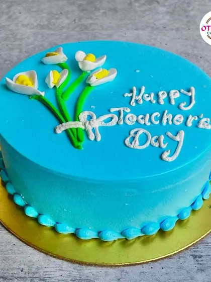 A simple and elegant blue cake with a hand-piped message and a bouquet of flowers, perfect for showing your appreciation on Teacher's Day.