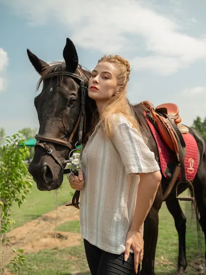 A model stands beside a dark horse, creating a striking contrast. Our diverse range of horses allows for different visual pairings to match any creative brief.