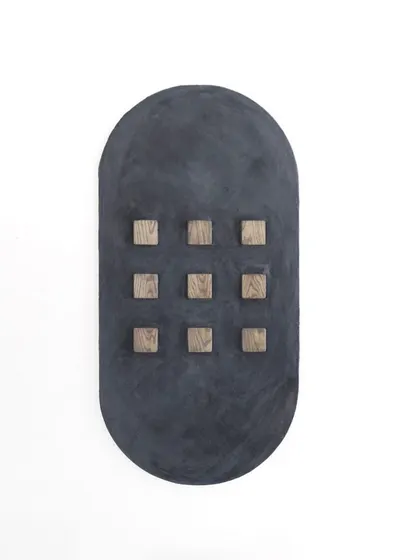 A direct, product-focused shot of the minimalist oval art, highlighting the contrast between the dark, textured base and the natural wood blocks.