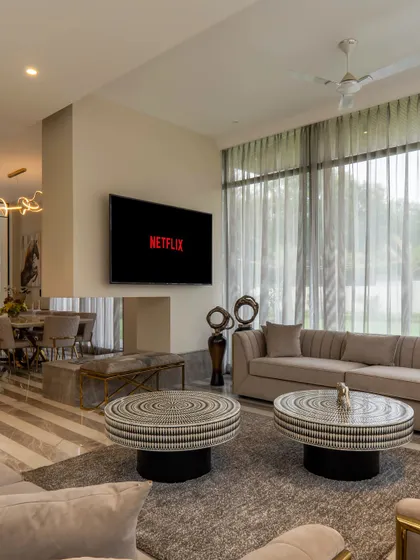 Elegance meets comfort in the drawing room of a modern farmhouse project. The serene and sophisticated space is defined by a palette of beige, white, and gold, with cozy furnishings that add the perfect touch of warmth for everyday living.