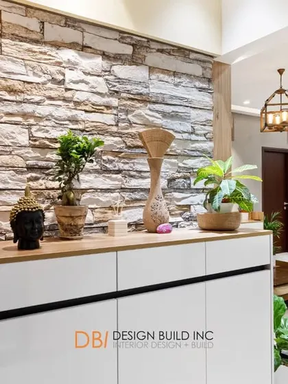 A perspective shot from behind the foyer cabinet, looking into the living room. The stone wall adds a rustic texture that contrasts beautifully with the modern furniture and lighting.