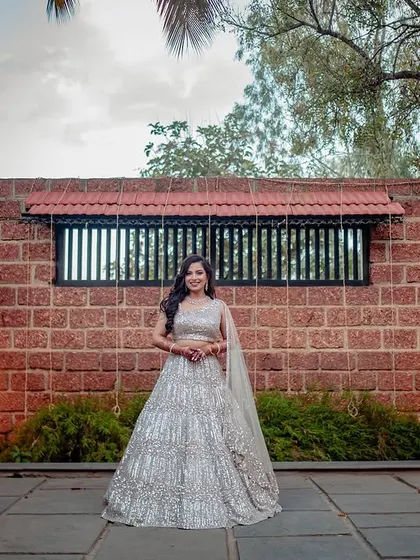 A full-length shot of Ashwini against the rustic brick wall of the reception venue.