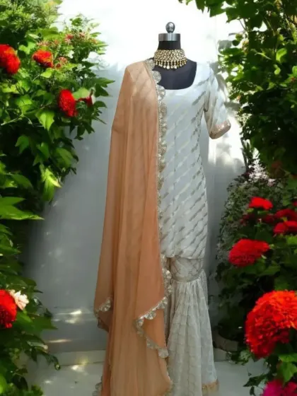 This ethereal cream sharara set is the epitome of dreamy elegance. Crafted in luxurious Burberry fabric with a soft organza dupatta, it's a light, airy, and graceful choice for any sun-kissed celebration or daytime wedding event. The delicate detailing gives it a timeless charm.