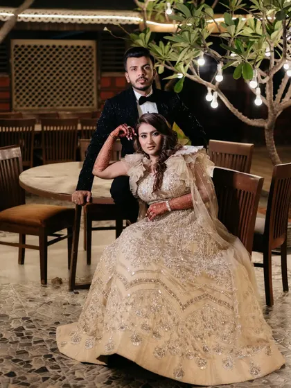 A regal portrait of Bhavi and Vishesh at their Sangeet, seated under a beautifully lit tree, looking like modern-day royalty.