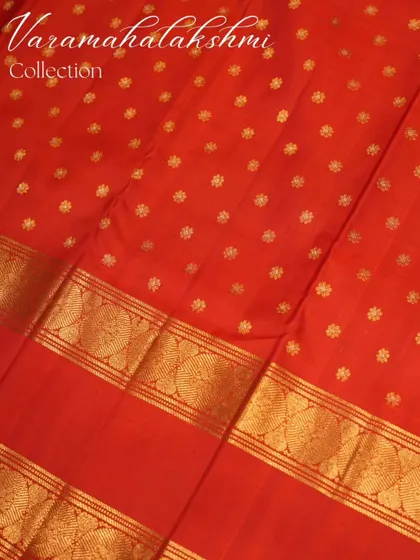 The body of the red saree is adorned with delicate gold buttas, adding to its festive charm.