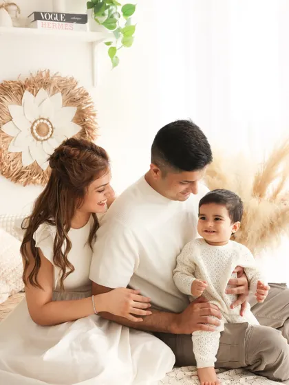 A calm and loving family portrait in our boho studio. The parents look on adoringly at their little one, creating a feeling of warmth, safety, and togetherness.
