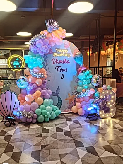 A different perspective of the mermaid-themed birthday party, showing the beautiful cascade of pastel balloons and the detailed backdrop design.