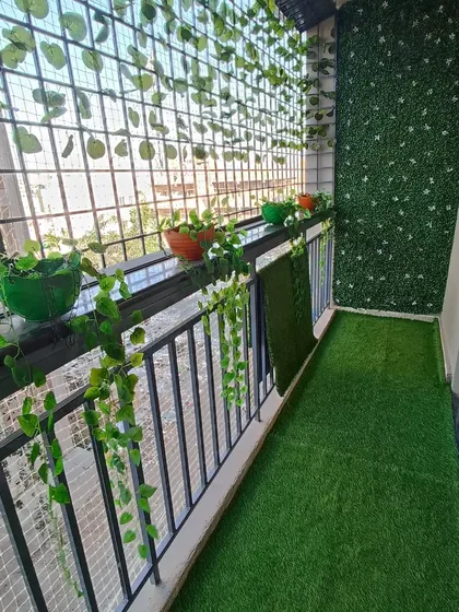 A complete look at a decorated balcony. The setup includes an artificial lawn, a green wall, and various hanging and potted plants, demonstrating how different elements can work together.