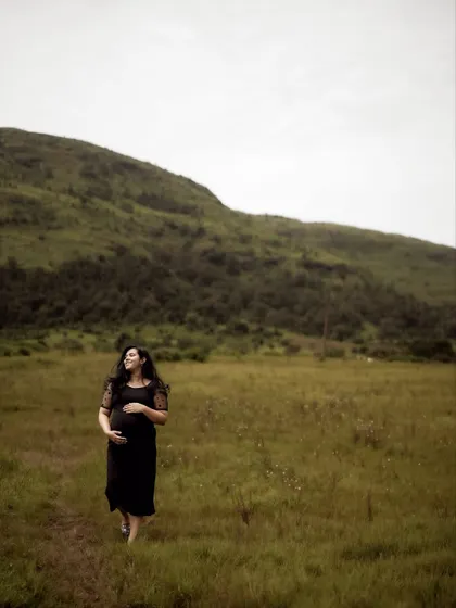 A beautiful wide shot of the mom-to-be walking through a field, cradling her bump. The vast landscape emphasizes the personal and profound journey she is on.