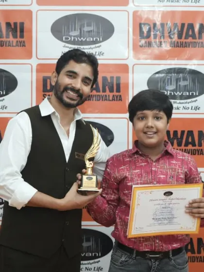 A teacher and student share a proud moment with a certificate and trophy.