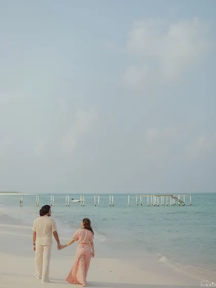 A classic romantic pose, walking away from the camera along the shoreline. This composition creates a sense of a shared future and endless possibilities.