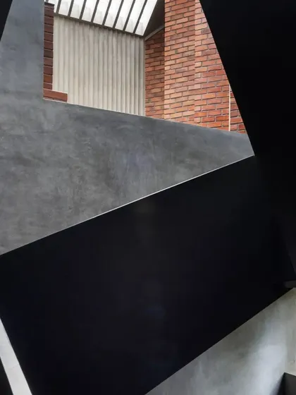 An abstract view of the Brick House staircase, where intersecting planes of black and grey create a complex geometric composition.