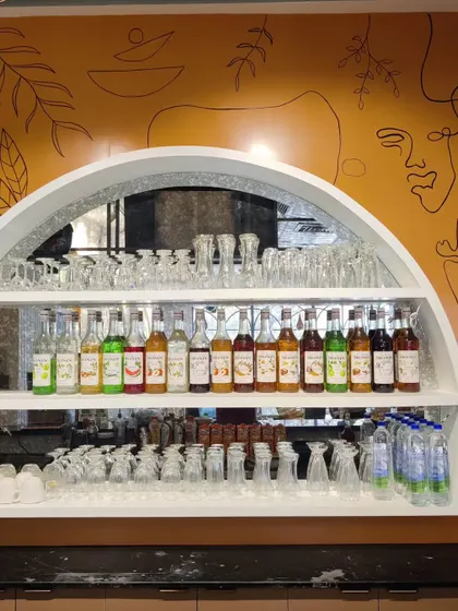The bar area at Cafe Berni, where my freehand line art on a mustard-colored wall serves as a backdrop to the bottle display. The abstract faces and botanicals add a layer of artistic detail.