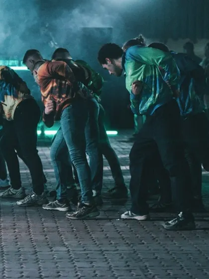 The dancers in a powerful, athletic stance. The performance showcases the physicality and raw energy of post-internet dance styles like jumpstyle.