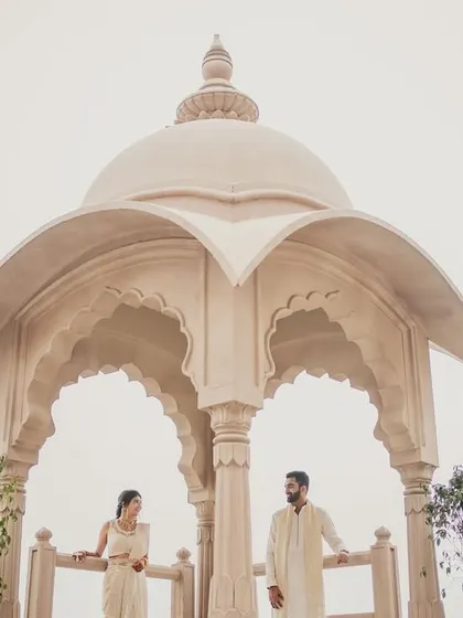 The couple posing under a beautiful Rajasthani-style dome at their Jaipur wedding venue.