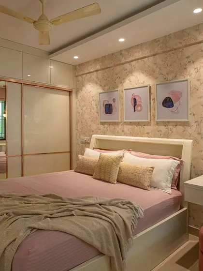 A bedroom makeover for two sisters, featuring soft pink bedding and a delicate floral wallpaper. The sliding wardrobe with rose gold trim and a mirrored panel makes the room feel larger and brighter.